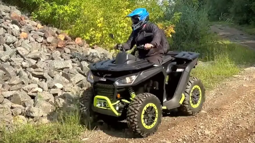 Rider on a black and green Segway Snarler AT6, driving on a rocky road in the open air.