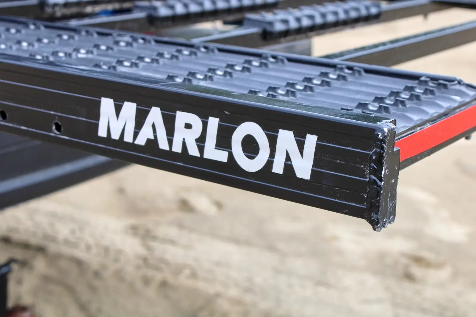 Close-up of a black Marlon loading ramp with non-slip patterns and a red edge.