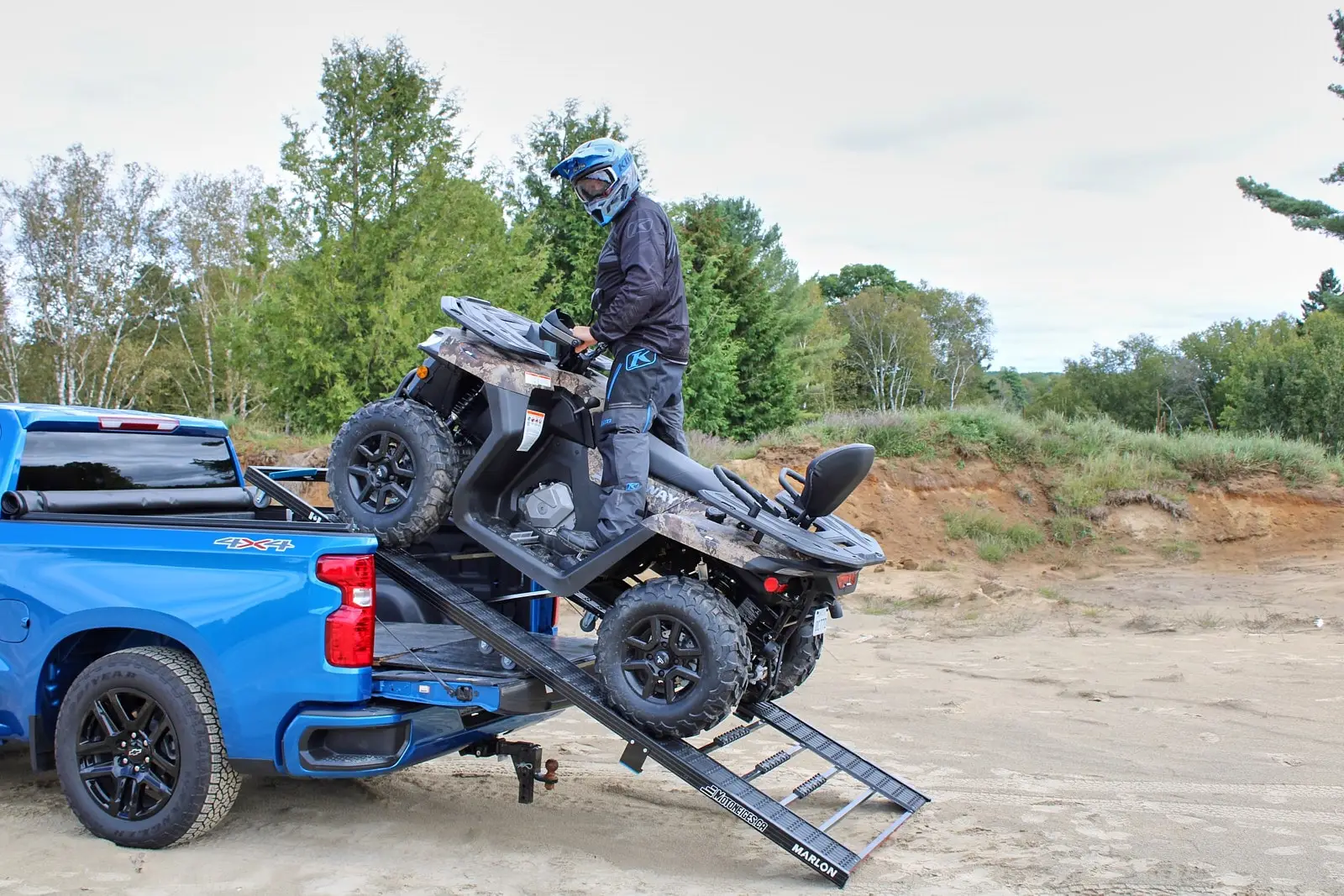 Personne en équipement de protection bleu chargeant un VTT Segway camouflé dans le plateau d’un pick-up bleu à l’aide d’une rampe Marlon.